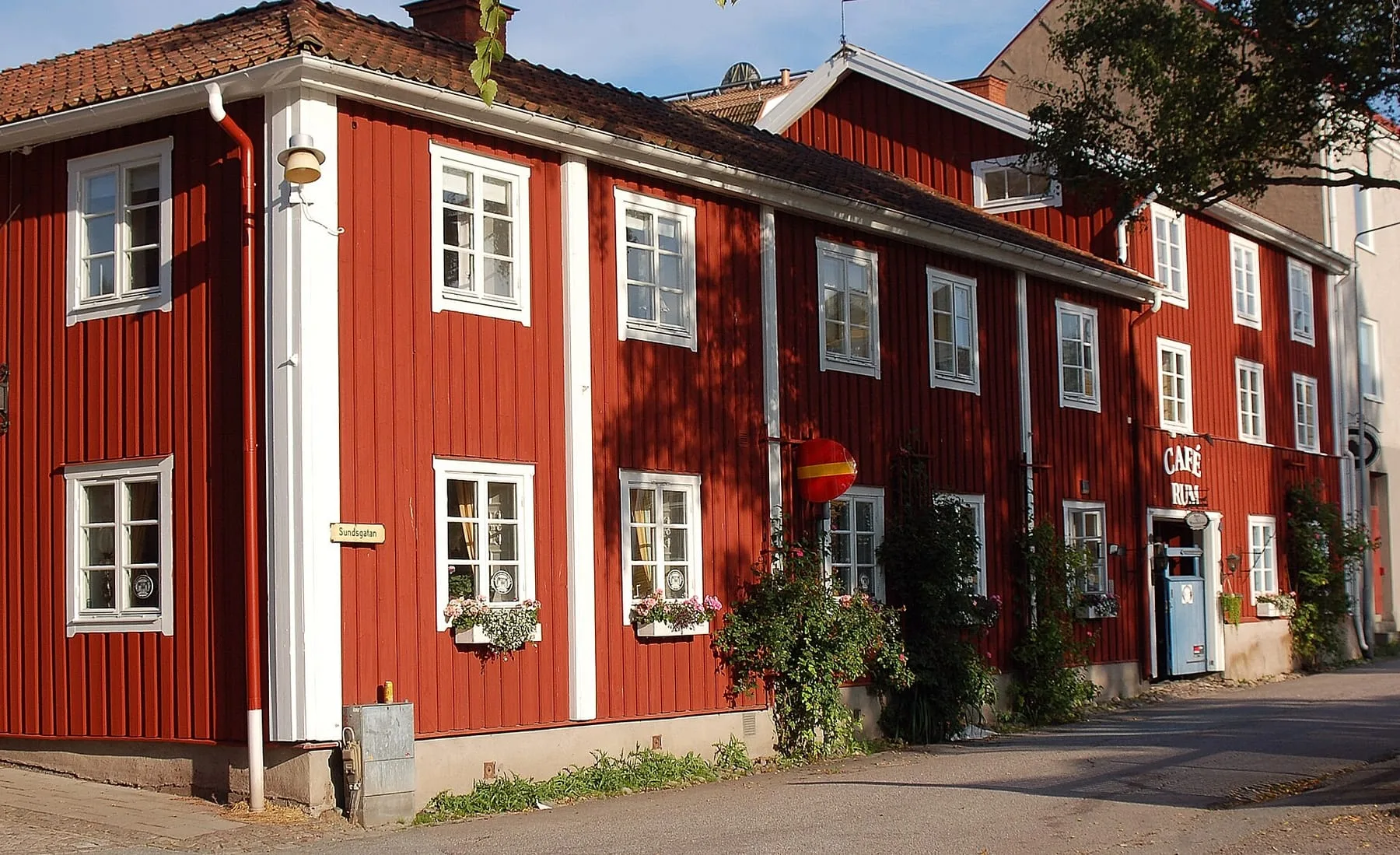 Garvaregården, ett rött trähus i två våningar med vita fönsterfoder och rosor längs fasaden.